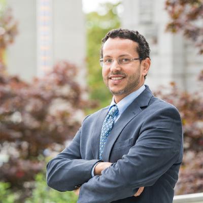 Dr. Muhammad Abdul-Mageed stands with his arms crossed, smiling